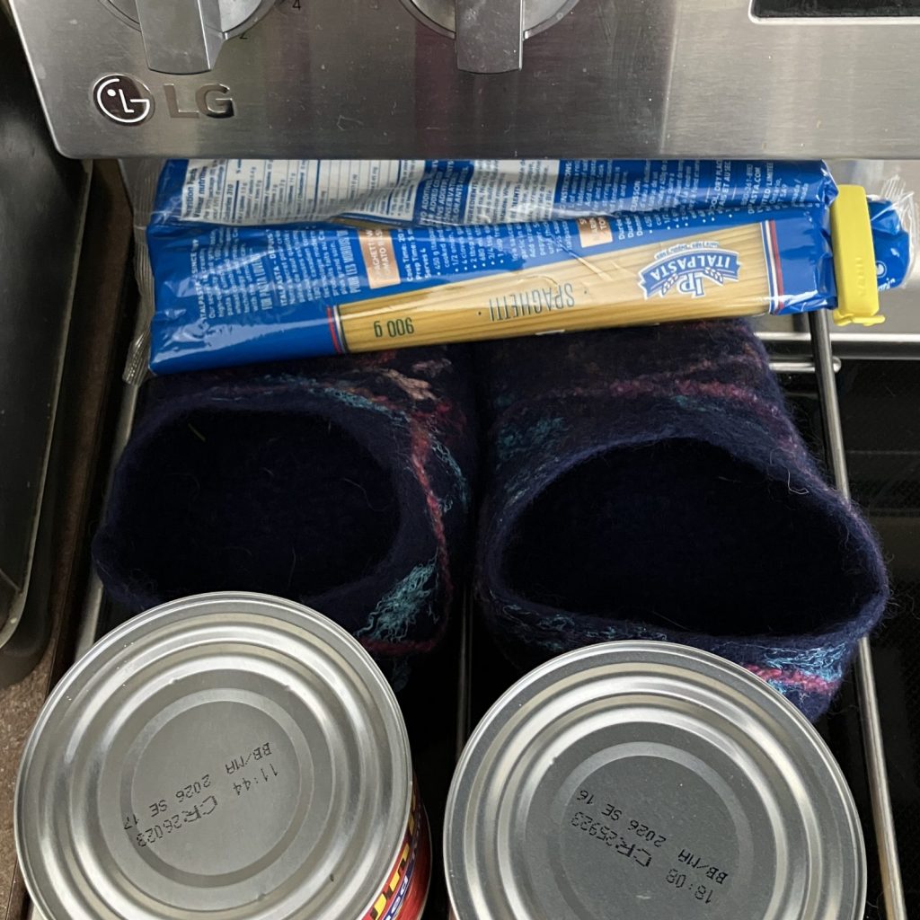 Wet felted slippers being squashed by canned goods and spaghetti