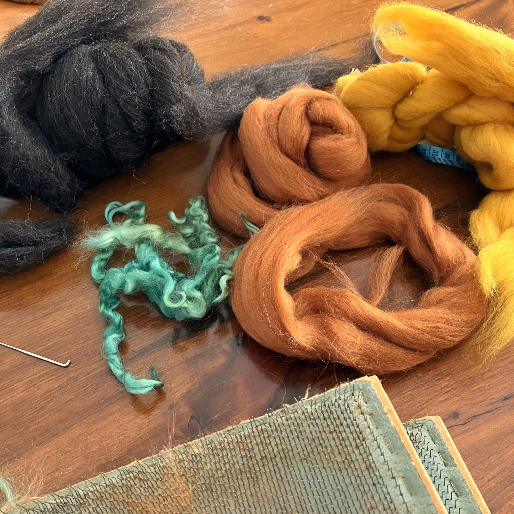 Loose wool roving in shades of brown and yellow and some teal locks