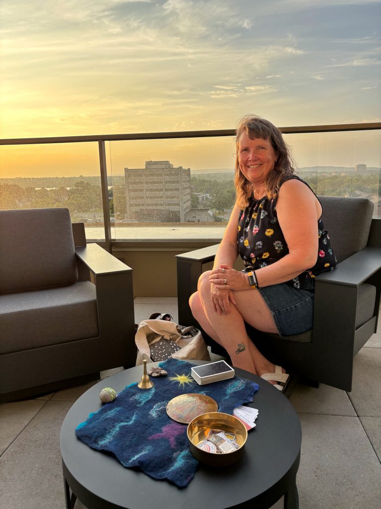 Dani reading tarot cards at a party on a balcony overlooking the sunset