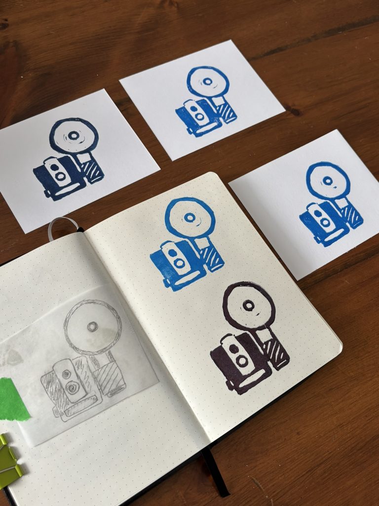 Image of a retro brownie camera block printed in a notebook and on a few cards in various shades of ink