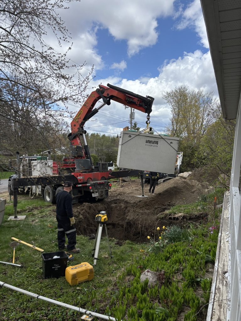 Concrete septic tank being lowered into a hole in the ground