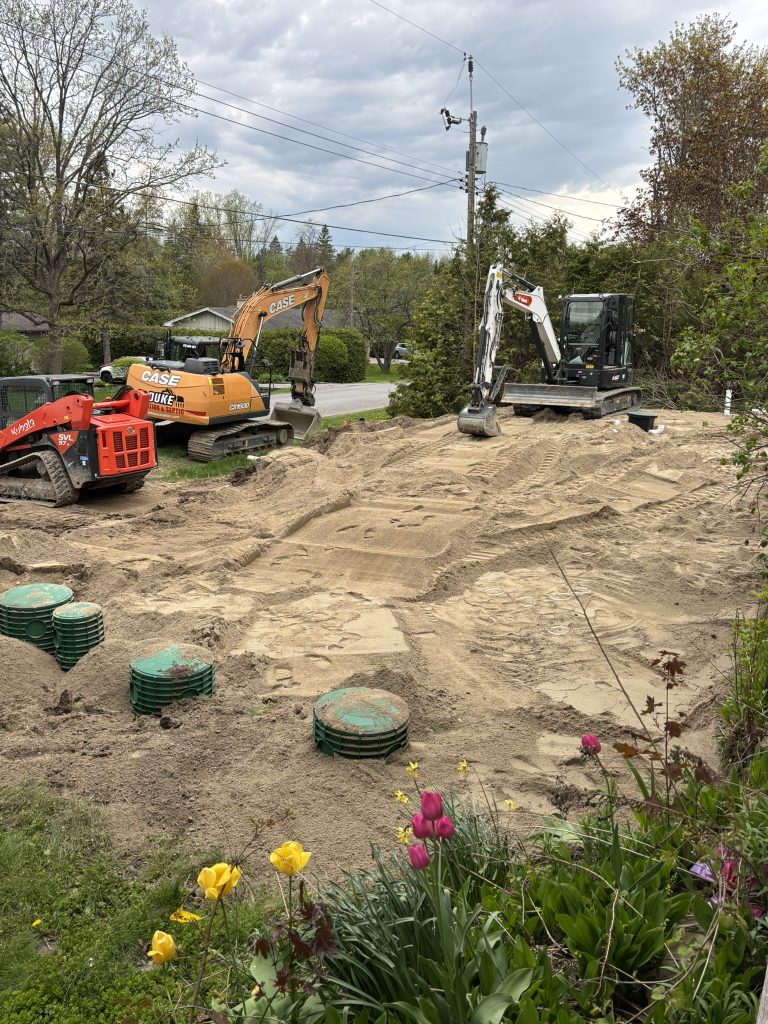 Excavators place septic sand over the yard