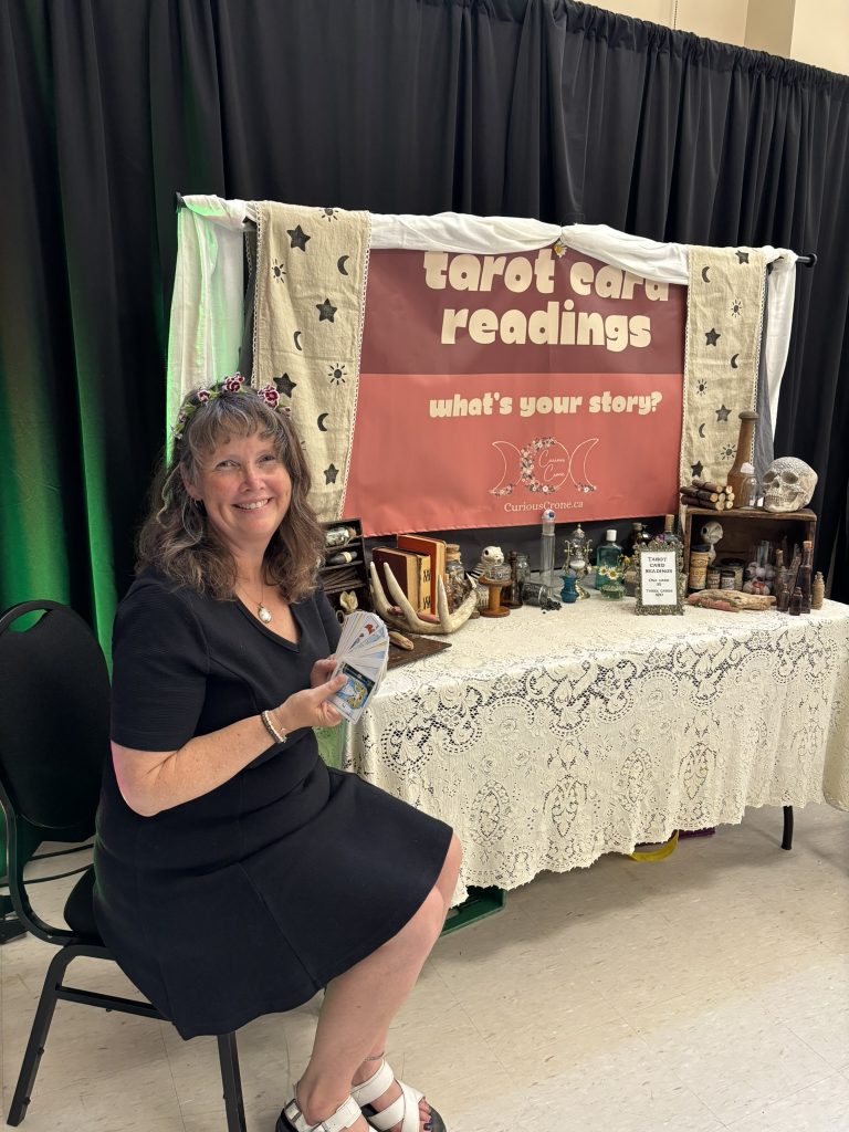 Dani Donders reading tarot cards at the alchemist-themed booth at a renaissance fair 