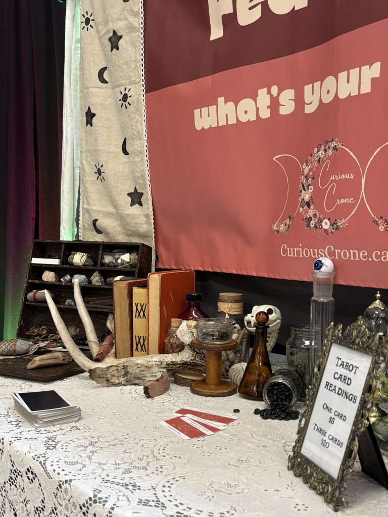 alchemist-themed tarot reading booth for a pop up renaissance fair including lace table cloth, bottles, antlers, and animal skeletons